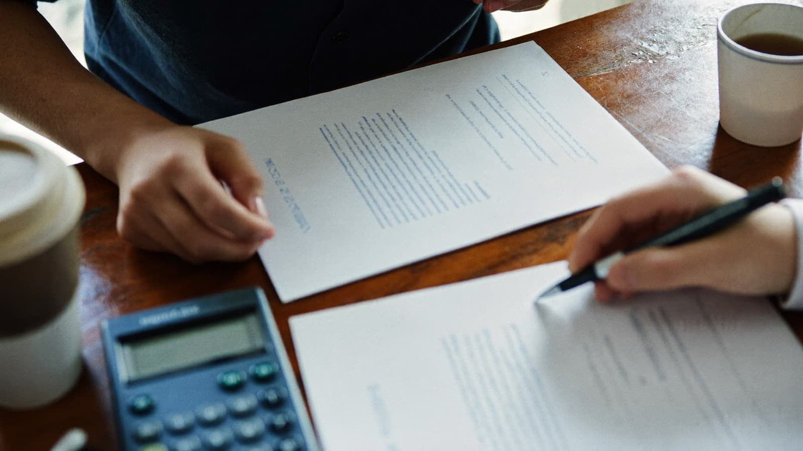 Two people comparing printed plan documents side by side at a table