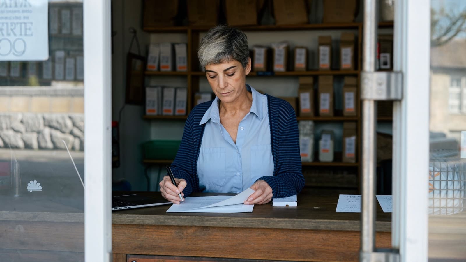 A small business owner doing paperwork behind her shop counter
